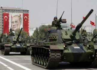 Turkish army tanks roll past a portrait of Mustafa Kemal Ataturk during a military parade in Ankara