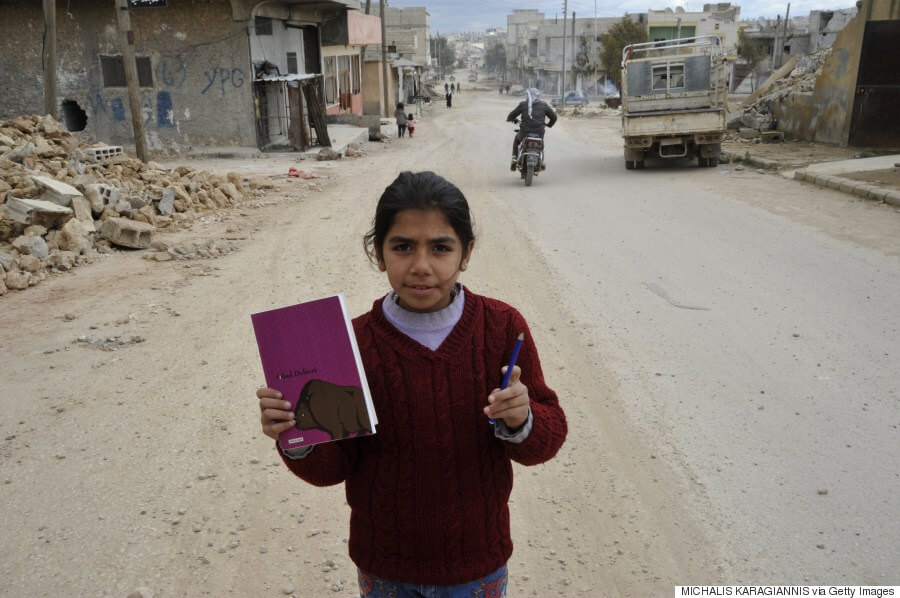 Seorang anak berpose dengan buku di distrik Kobane, yang dekat dengan wilayah kekuasaan ISIS. Sumber: AFP/Getty Images